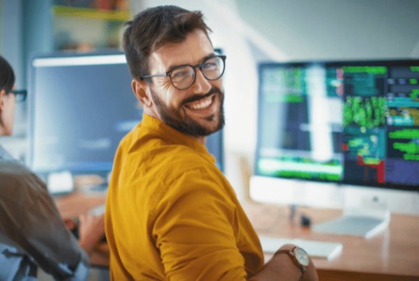 Un informaticien sur sa chaise de bureau se retournant souriant